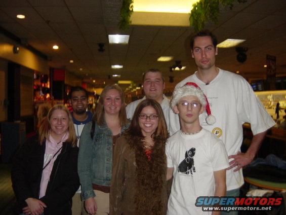 Group of people posing for a photo indoors, one wearing a Santa hat