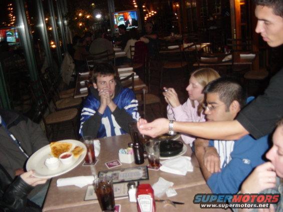 people sitting at tables in a restaurant, one person is holding a plate of food