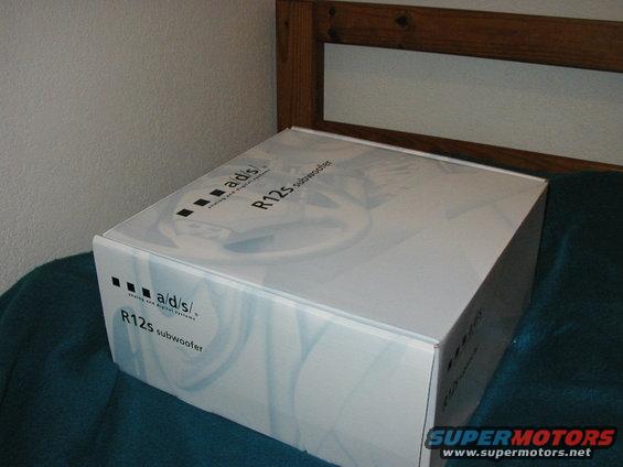 ADS R12s subwoofer box on a teal blanket with a wooden headboard in the background