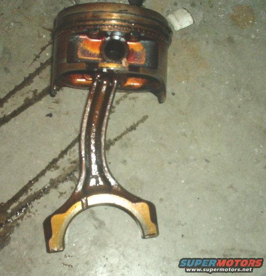 Piston and connecting rod assembly, likely from a damaged engine