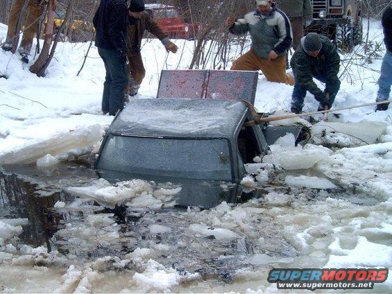 Car stuck in ice with people trying to pull it out
