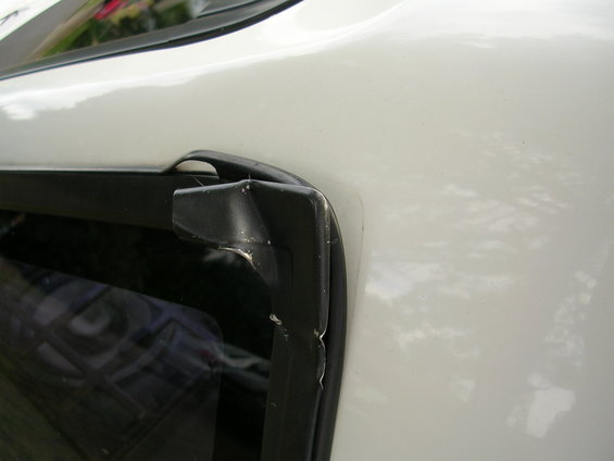 White car's black window trim with chipped paint and visible damage