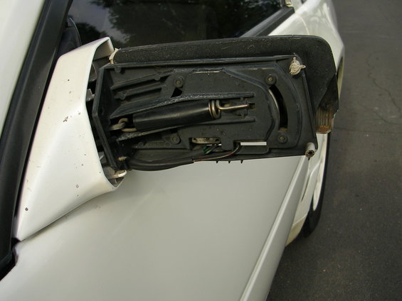 White 1989 Nissan 300ZX side mirror assembly detached, showing internal mechanism and wiring