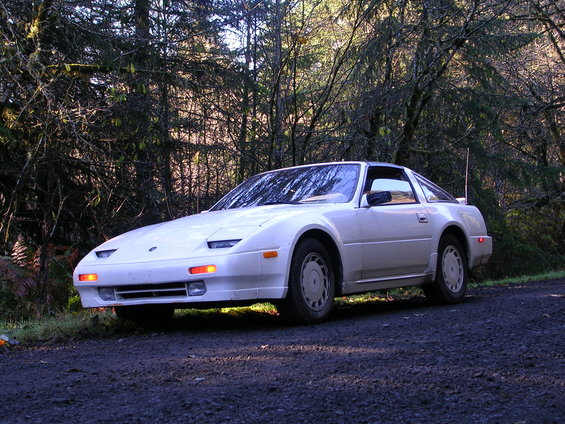 White 1984 Nissan 300ZX parked on a dirt road with trees in the background
