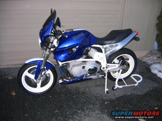 Blue motorcycle with white wheels and a front fairing, parked on asphalt