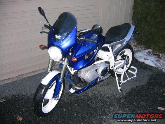 Blue motorcycle with white stripes on the front fender and fairing, parked on asphalt