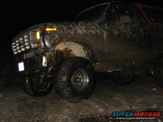 Mud-covered 1980s SUV front 3/4 view at night