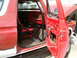 1979 Ford Bronco - Interior view of a red SUV with an open door, revealing a roll cage and engine bay.