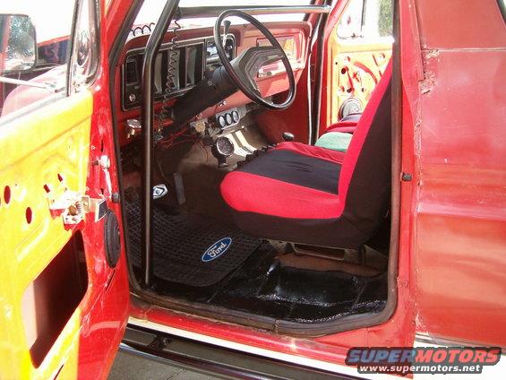 Red 1979 Ford Bronco interior with black and red seat covers and Ford floor mat