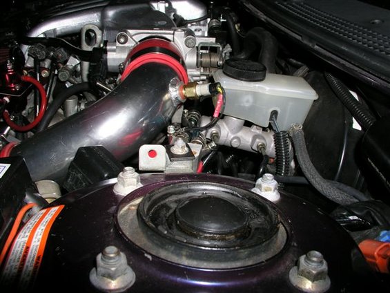 Engine bay with custom intake piping and brake fluid reservoir. Some warning labels are visible