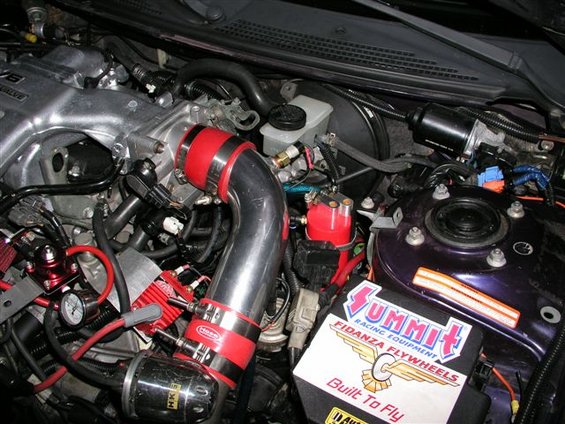 Engine bay with V6 intake manifold, red silicone couplers, and Summit Racing flywheel box