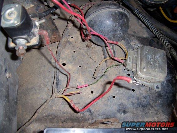 Close-up of engine bay wiring, including a solenoid, horn, and voltage regulator