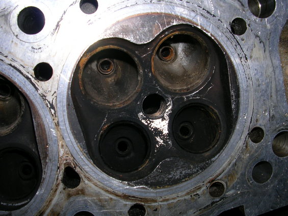 Engine cylinder head with four combustion chambers, showing carbon buildup and valve seats