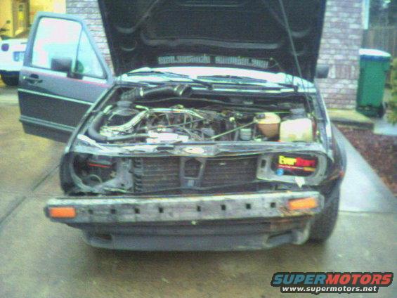 1987 Volkswagen Golf engine bay, hood open, front bumper removed. EverStart battery visible