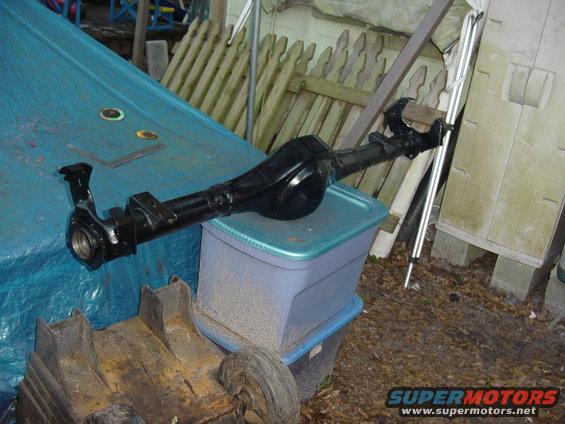 Black rear axle assembly on a blue tarp and plastic bin