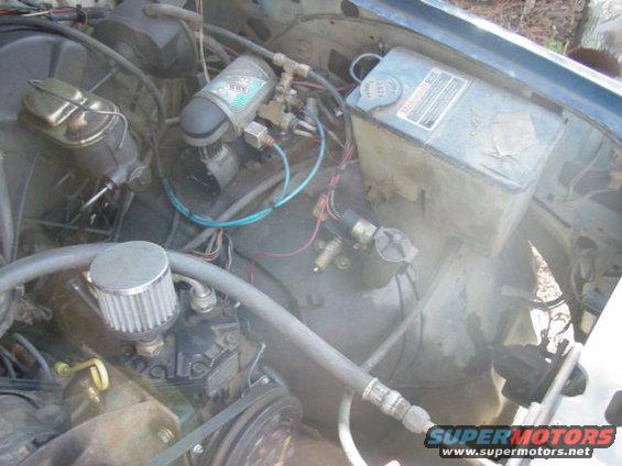 Engine bay showing air compressor, brake fluid reservoir, and hoses