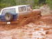 1978 Ford Bronco - A muddy 1978 Ford Bronco navigates a challenging off-road terrain.