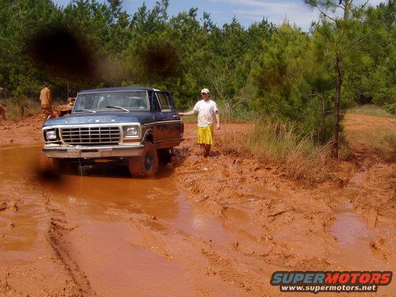 1978 Ford Bronco stuck in deep mud with a person standing next to it