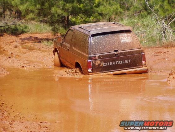 Muddy Chevrolet SUV stuck in a mud pit, 'For Sale' sign on back window