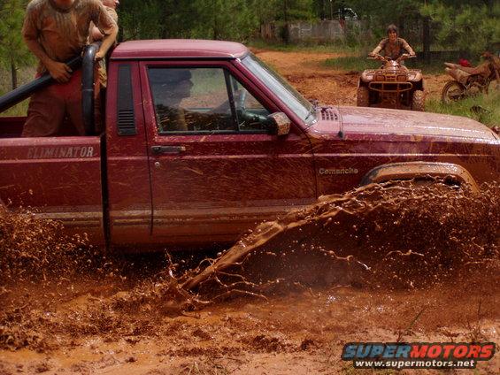 Red pickup truck splashing mud, with "Eliminator" and "Comanche" text visible