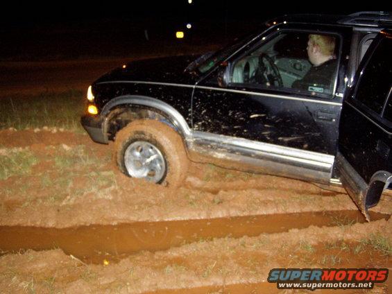 Black SUV stuck in mud with driver inside