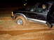 1978 Ford Bronco - Black SUV is stuck in deep mud with the driver visible inside.