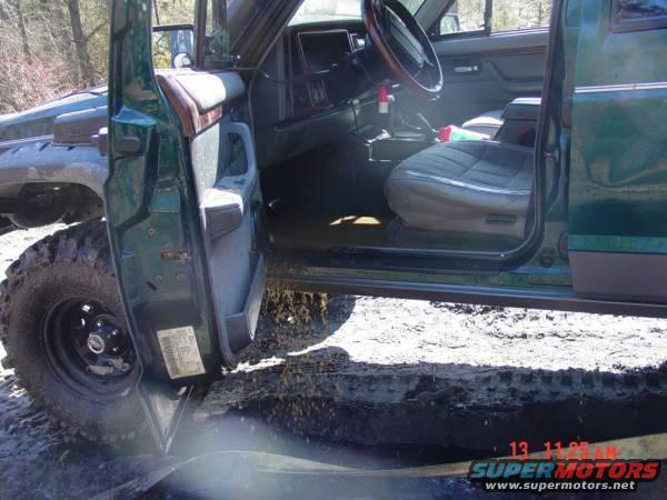 Green Jeep Cherokee interior with driver's seat and dashboard visible, door open, front tire and fender also visible