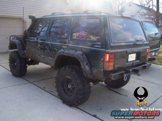 Dark green Jeep Cherokee XJ with snorkel, fender flares, and large tires, parked on a driveway