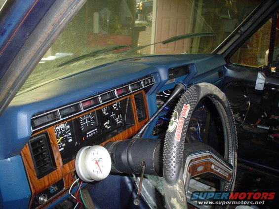 Dashboard and steering wheel of a vehicle, with aftermarket gauge and Mossy Oak steering wheel cover