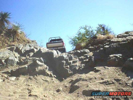 Truck going up a rocky hill. Supermotors.net logo in corner
