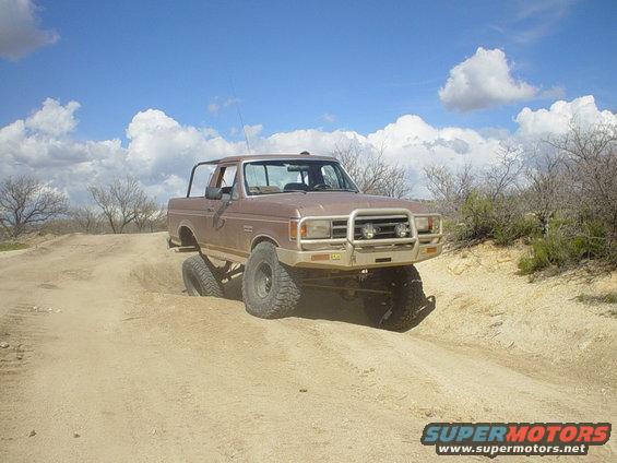 Brown 1989 Ford Bronco off-roading on a dirt hill