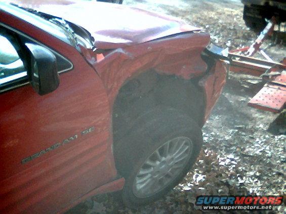 red sedan, possibly a Grand Am SE, with significant damage to the front fender and hood. A tow hitch is visible in the background