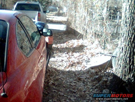 red car parked next to white pickup truck on a leaf-covered street