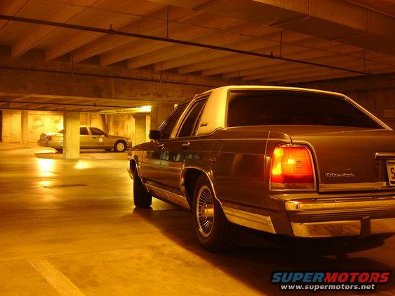 Rear view of a brown 1980s Ford sedan parked in a garage, another car visible in background