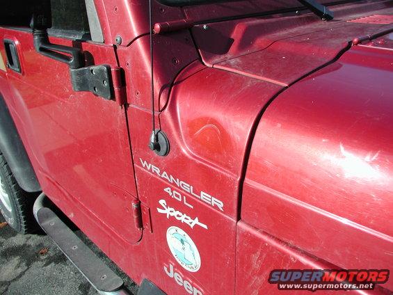 Side view of a red 1998 Jeep TJ Wrangler Sport 4.0L with a decal on the door