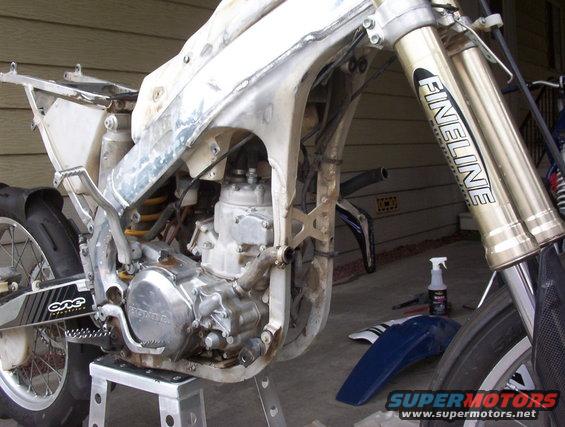 Honda dirt bike frame with engine exposed, front forks visible. Looks like it's being worked on