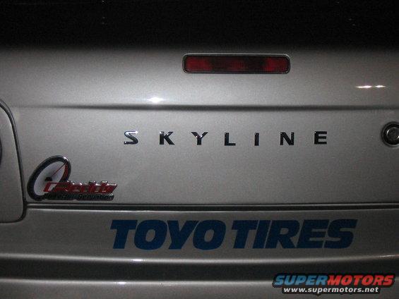 Silver car trunk with SKYLINE badging and TOYO TIRES sticker