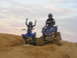 2003 Yamaha RAPTOR 660 - Two riders on blue ATVs navigate a sandy terrain with a cloudy sky above.