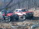 1986 Ford Bronco - Two off-road vehicles, a Ford Bronco and a Jeep, are parked on a trail surrounded by trees.