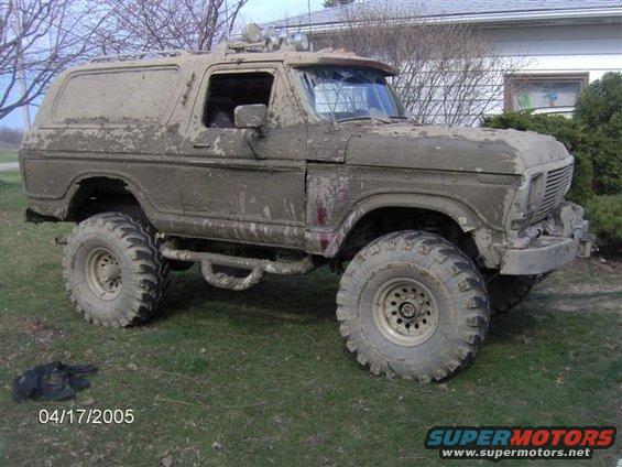Mud-covered 1978 Ford Bronco with large tires and off-road lights, viewed from the front three-quarter angle