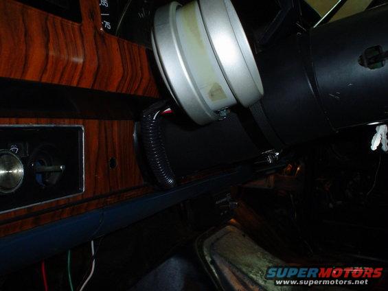 1984 Ford Bronco interior with wood-grain dash and an aftermarket gauge mounted to the steering column