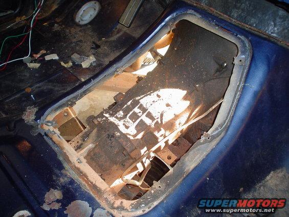 Vehicle interior floor pan showing open transmission tunnel and exposed components. Wires are visible