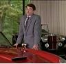 Man in suit by red car, classic car in background