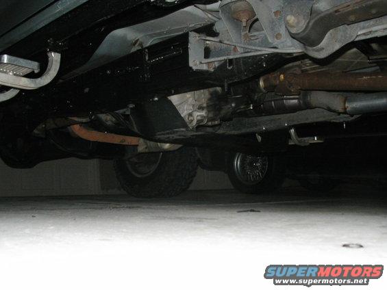Undercarriage of a vehicle showing the transmission, exhaust system, and tires. The frame is painted black