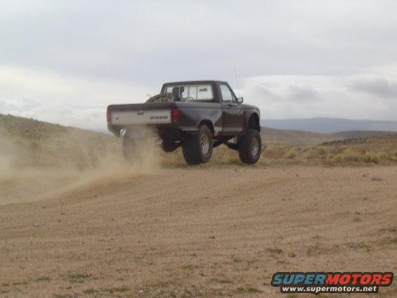 1985 Ford Ranger lifted and kicking up dust on a dirt hill