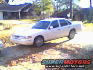 White 1995 Ford Crown Victoria sedan, front 3/4 view, parked on dirt lot