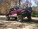 2001 Dodge 1500 - Red 2001 Dodge 1500 pickup truck with off-road modifications is positioned on a dirt path.