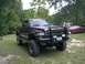 2001 Dodge 1500 - Lifted Dodge pickup truck with bull bar and aftermarket wheels is parked on grass with a red sedan in the background.