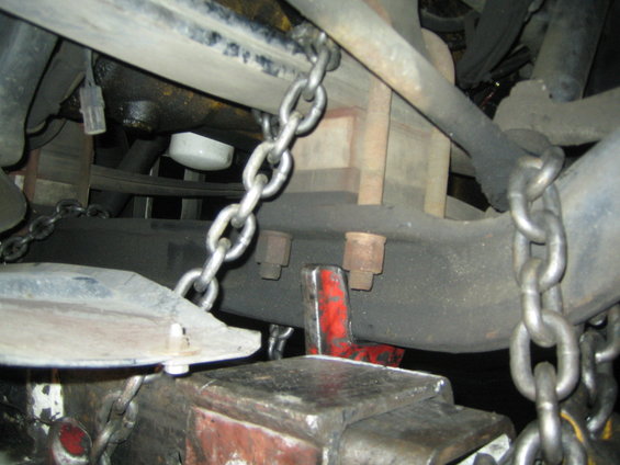 Chains securing a vehicle's undercarriage, showing suspension components and an oil filter