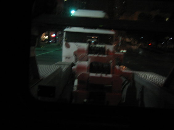 Tow truck with a large winch mechanism on the back, seen at night